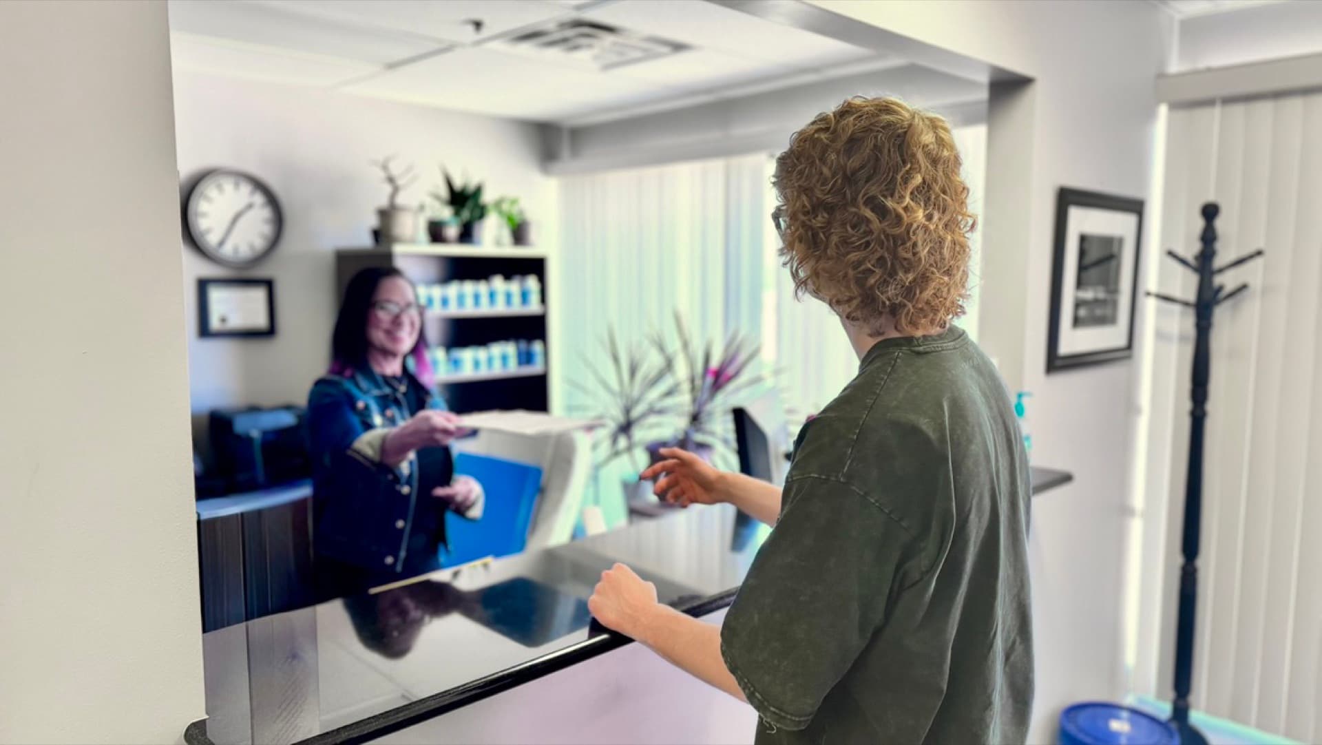 Jamie welcoming a new patient and receiving intake forms at Advanced Chiropractic and Neurology reception in La Vista, NE